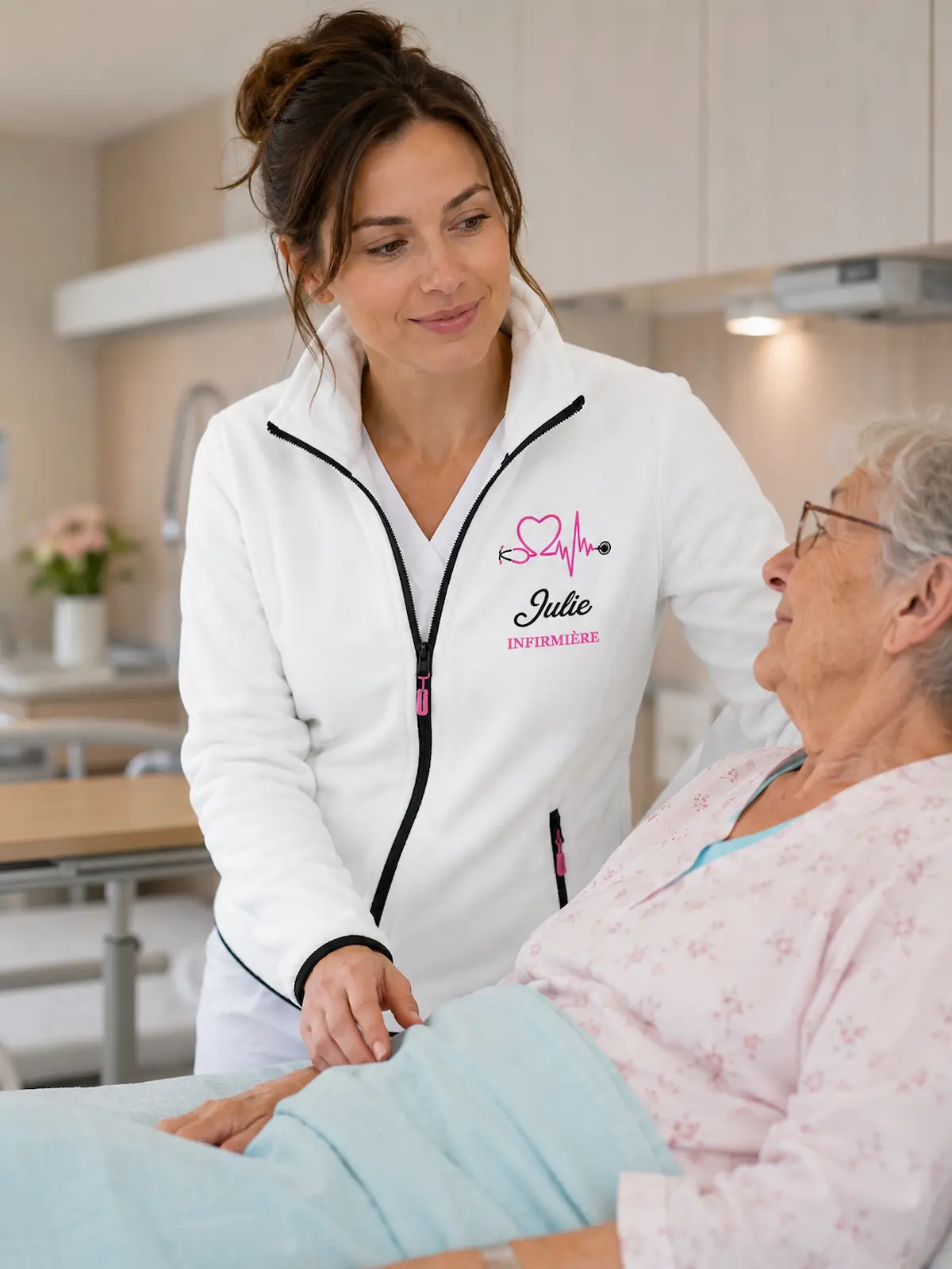 Infirmière portant une veste polaire personnalisée Curalini auprès d’une patiente à l’hôpital