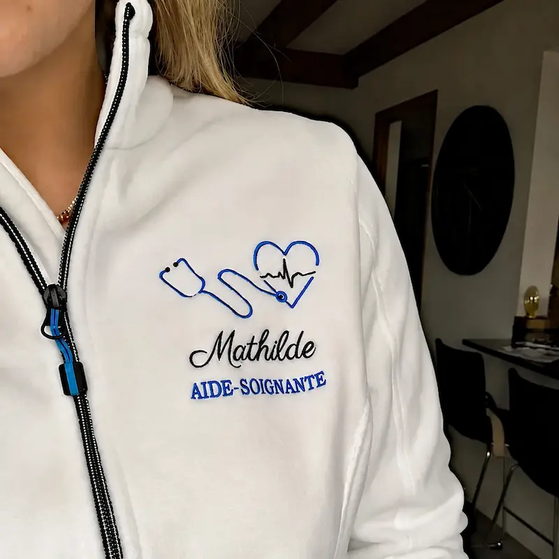 Mathilde portant sa veste polaire personnalisée blanche d’aide-soignante Curalini