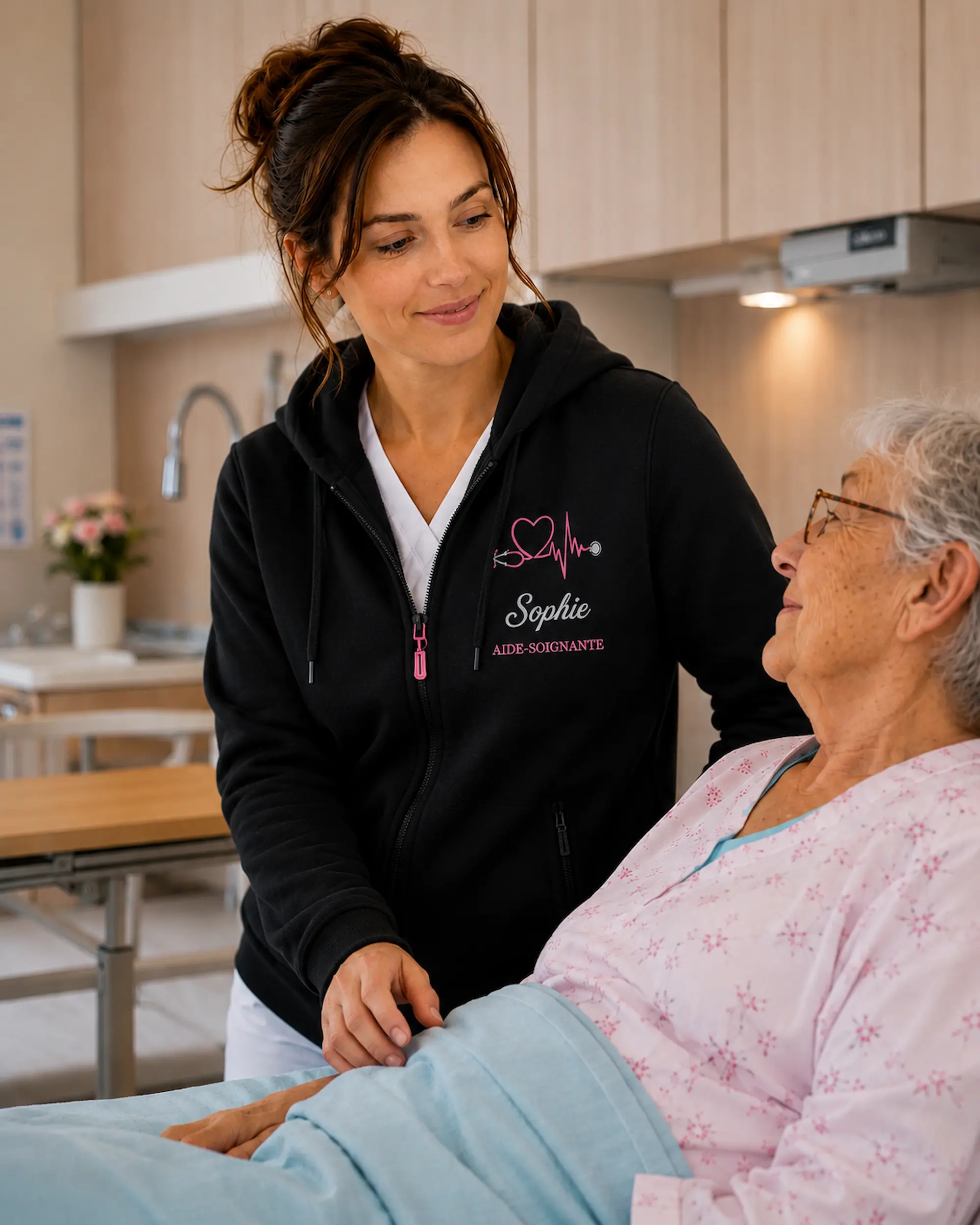 Sophie aide-soignante portant un sweat femme personnalisé Curalini auprès d'une patiente