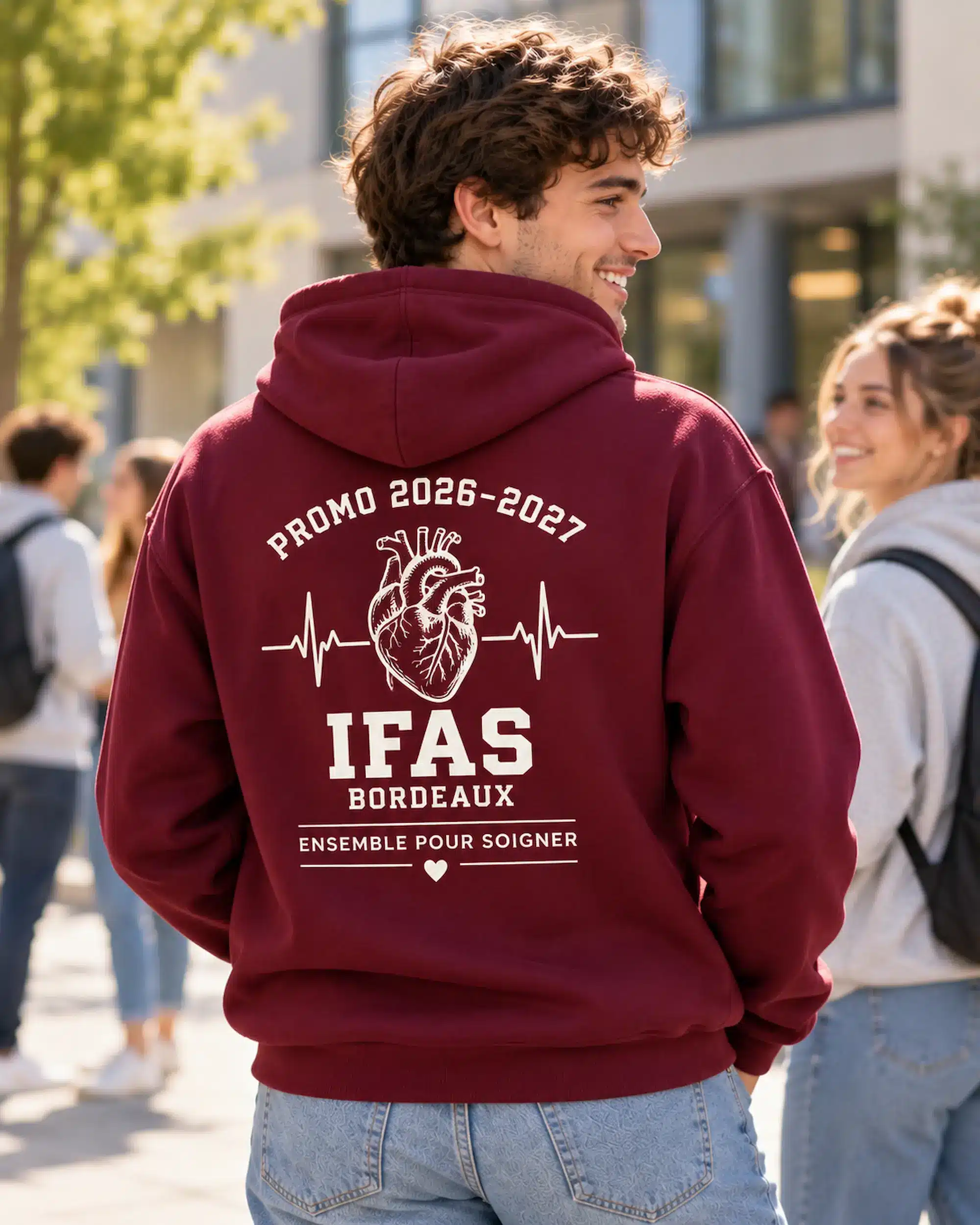 Étudiant portant un sweat à capuche bordeaux personnalisé au dos avec un motif de cœur et l’inscription Ensemble pour soigner.