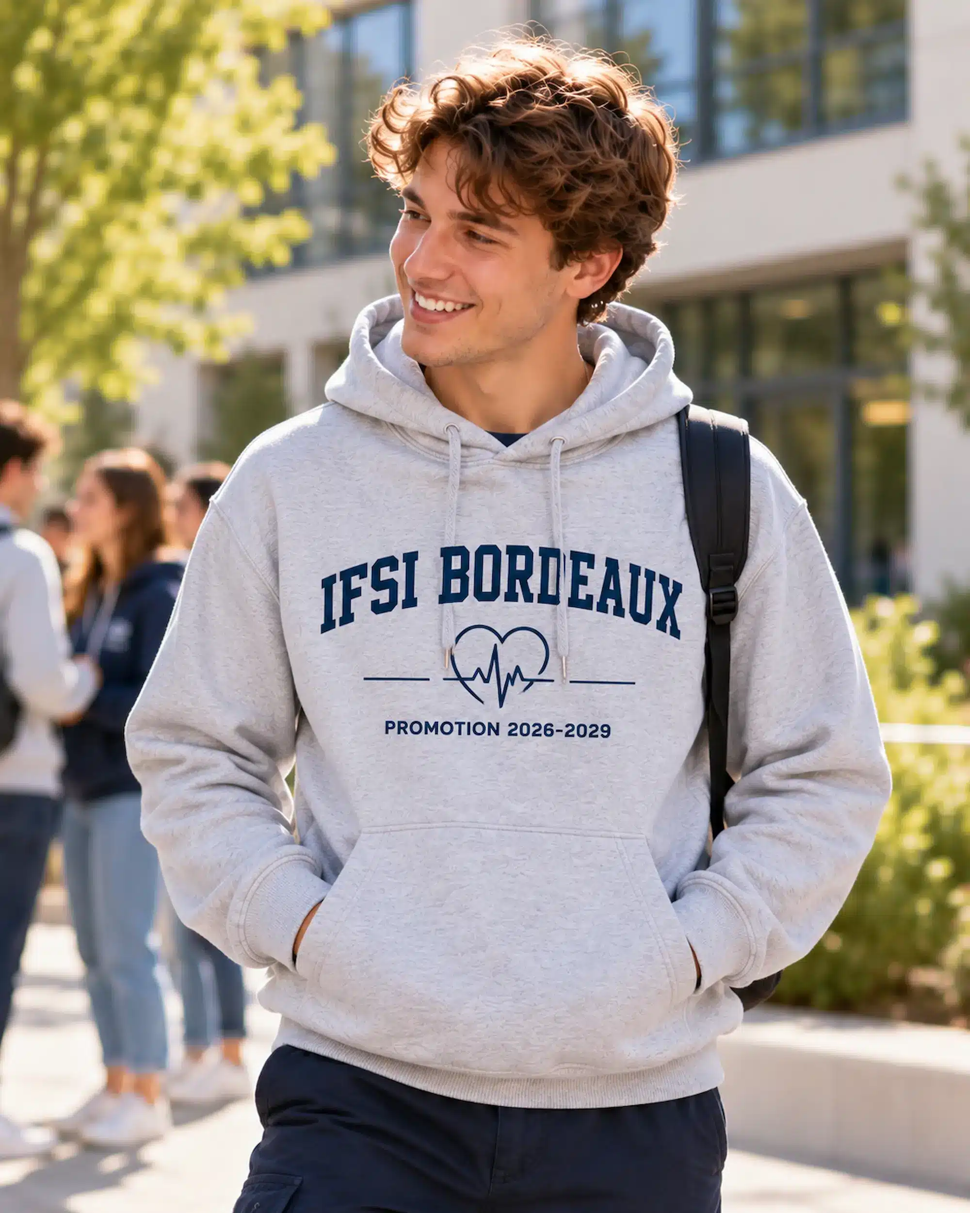 Étudiant portant un sweat à capuche gris Oxford avec impression bleu marine IFSI Bordeaux, cœur ECG et Promotion 2026–2029.