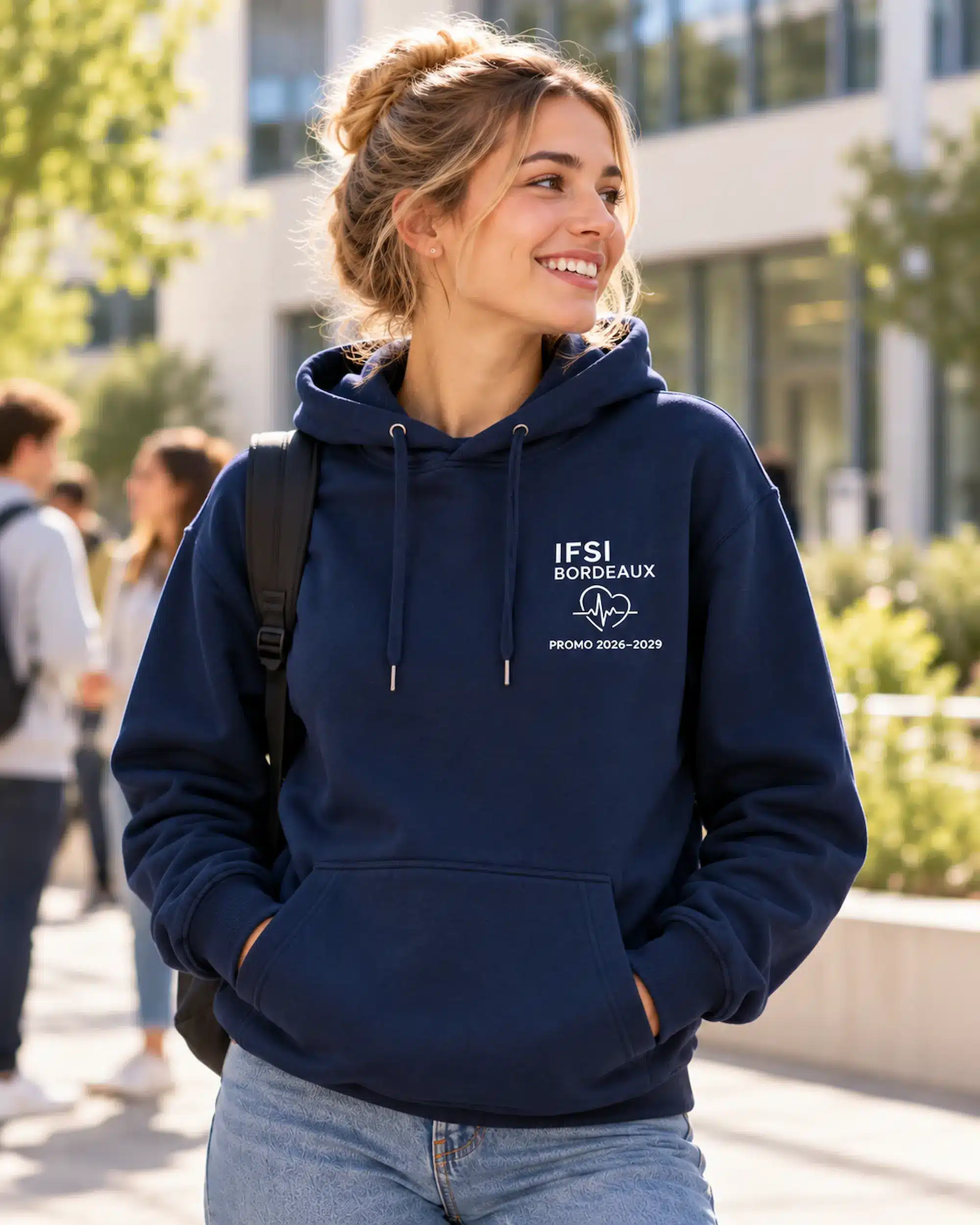Étudiante portant un sweat à capuche bleu marine personnalisé avec IFSI Bordeaux, un cœur ECG et les années de promotion 2026–2029.